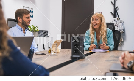 Happy mature businesswoman discussing strategy with colleagues during meeting 126033609