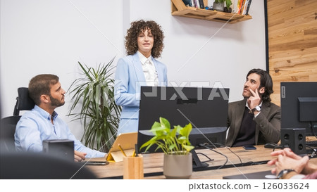 Confident businesswoman explaining strategy to male colleagues in office Confident businesswoman explaining strategy to male colleagues in office 126033624