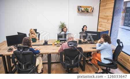 Group of creative businesspeople discussing at computer desks in office 126033647