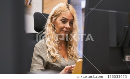 Smiling blond businesswoman using tablet computer in office Smiling blond businesswoman using tablet computer in office 126033653