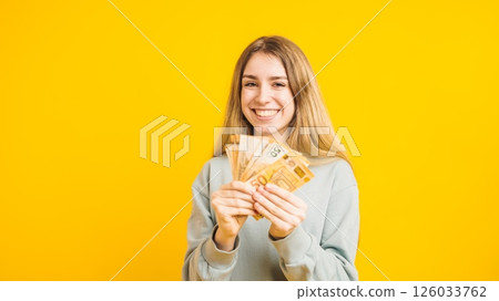 Happy woman holding euro banknotes on yellow background 126033762