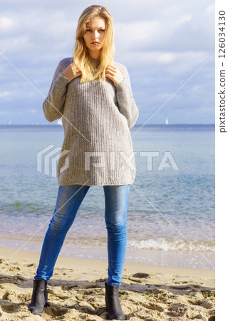 Woman in sweater walking on beach 126034130