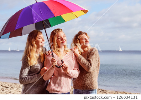 Three women under colorful umbrella 126034131