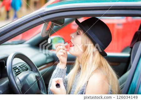 Young woman applying lipstick in car Young woman applying lipstick in car 126034149