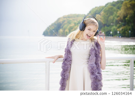Happy woman wearing headphones outdoor 126034164