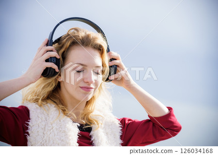 Happy woman wearing headphones outdoor 126034168
