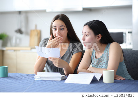 Amazed interracial women checking bank statement at home Amazed interracial women checking bank statement at home 126034825