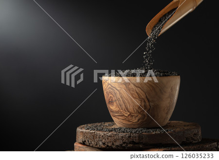 Black sesame is poured in wooden bowl. 126035233