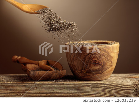 Chia seeds is poured into a wooden bowl. 126035239