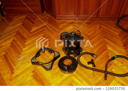 Disassembled vacuum cleaner with water filter on a parquet floor. Disassembled vacuum cleaner with water filter on a parquet floor. 126035730