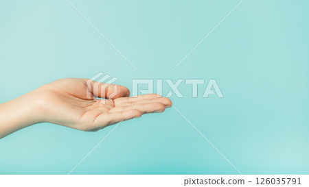 Close up of female hand holding something on blue background with copy space 126035791
