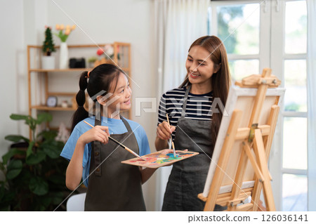Creative bonding activity: Mother and daughter painting together in a cozy environment Creative bonding activity: Mother and daughter painting together in a cozy environment 126036141