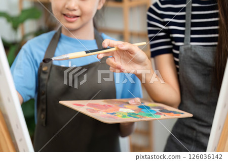 Creative bonding through art: Mother and daughter sharing paint colors Creative bonding through art: Mother and daughter sharing paint colors 126036142