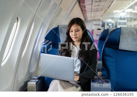 Business travel: Young woman concentrating while using a laptop on a flight 126036195