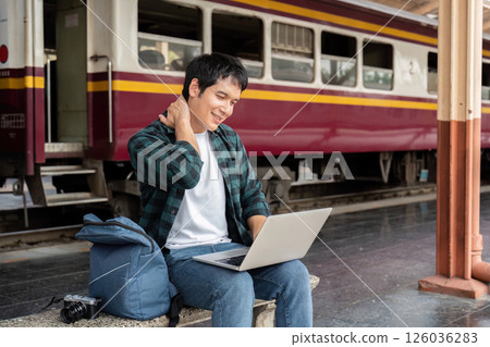 Digital Connection and Travel. A young man working on a laptop at the train station. Digital Connection and Travel. A young man working on a laptop at the train station. 126036283