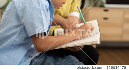 Mother and Son Back to School. A mother helps her son with homework, fostering a supportive learning environment. 126036476