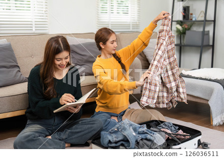 Friendship and sharing joy while organizing a travel suitcase Friendship and sharing joy while organizing a travel suitcase 126036511