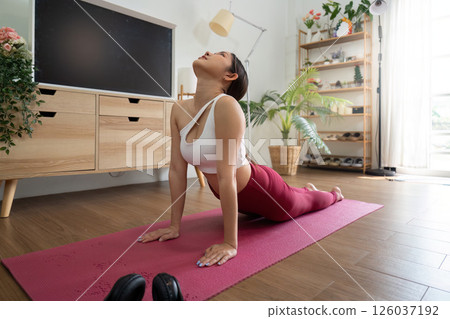 Yoga and Exercise. A focused woman practicing yoga in a serene indoor environment. Yoga and Exercise. A focused woman practicing yoga in a serene indoor environment. 126037192