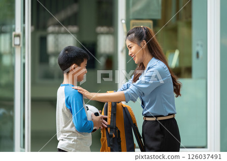 Back to School and Family Bonding. A mother greets her son after school, showcasing their warm relationship. 126037491