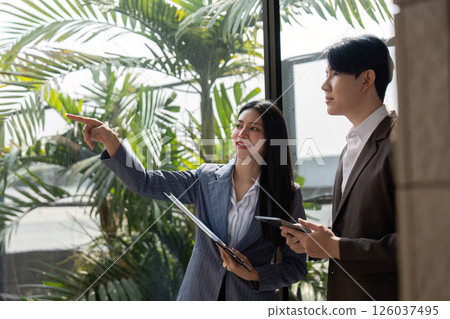 Team members discussing and analyzing ideas with sticky notes and charts in a modern office. Team members discussing and analyzing ideas with sticky notes and charts in a modern office. 126037495