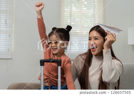Family Travel Excitement and Preparation. A joyful mother and daughter show enthusiasm for an upcoming trip. 126037503