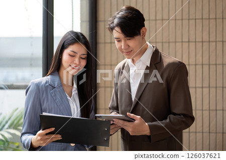 Engaged teamwork. Business professionals reviewing project documentation and digital data in a modern office setting. 126037621