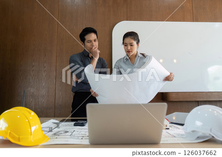 Design and Analysis. Engineers analyzing blueprints together for a construction project. Design and Analysis. Engineers analyzing blueprints together for a construction project. 126037662