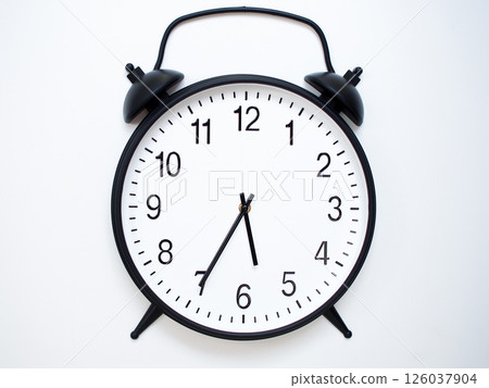 Black Retro Alarm Clock Showing 05:35 or 17:35. Classic Bell Style on White Wood Background. Black Retro Alarm Clock Showing 05:35 or 17:35. Classic Bell Style on White Wood Background. 126037904