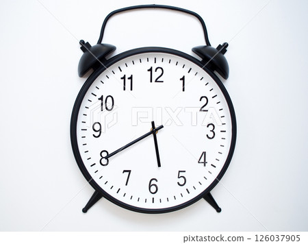 Black Retro Alarm Clock Showing 05:40 or 17:40. Classic Bell Style on White Wood Background. Black Retro Alarm Clock Showing 05:40 or 17:40. Classic Bell Style on White Wood Background. 126037905