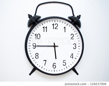 Black Retro Alarm Clock Showing 05:45 or 17:45. Classic Bell Style on White Wood Background. Black Retro Alarm Clock Showing 05:45 or 17:45. Classic Bell Style on White Wood Background. 126037906