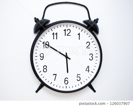 Black Retro Alarm Clock Showing 05:50 or 17:50. Classic Bell Style on White Wood Background. Black Retro Alarm Clock Showing 05:50 or 17:50. Classic Bell Style on White Wood Background. 126037907