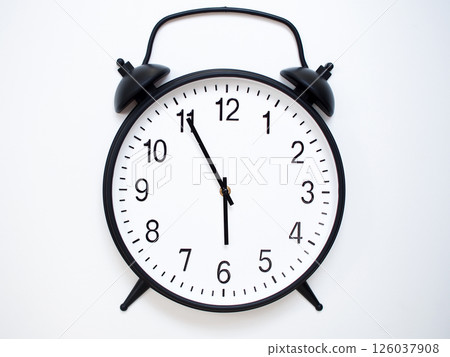 Black Retro Alarm Clock Showing 05:55 or 17:55. Classic Bell Style on White Wood Background. Black Retro Alarm Clock Showing 05:55 or 17:55. Classic Bell Style on White Wood Background. 126037908