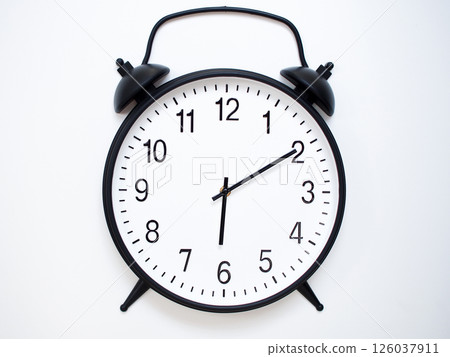 Black Retro Alarm Clock Showing 06:10 or 18:10. Classic Bell Style on White Wood Background. 126037911