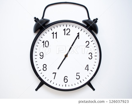 Black Retro Alarm Clock Showing 07:05 or 19:05. Classic Bell Style on White Wood Background. Black Retro Alarm Clock Showing 07:05 or 19:05. Classic Bell Style on White Wood Background. 126037923