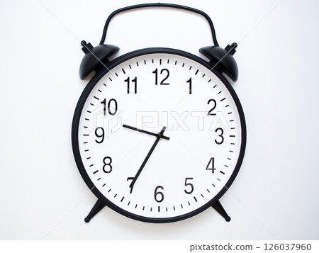 Black Retro Alarm Clock Showing 09:35 or 21:35. Classic Bell Style on White Wood Background. 126037960
