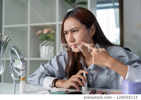 Skin Concern and Beauty Routine. A woman examines her skin in front of a mirror, addressing beauty concerns with focused attention. Skin Concern and Beauty Routine. A woman examines her skin in front of a mirror, addressing beauty concerns with focused attention. 126038133