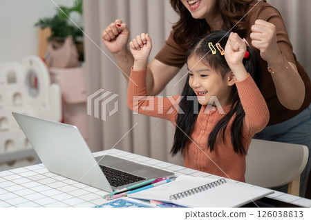 Back to School and Celebrating Success. A child rejoices after completing an online task with parental support. Back to School and Celebrating Success. A child rejoices after completing an online task with parental support. 126038813