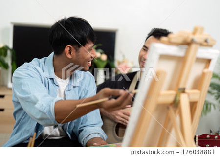 Gay couple creating art and enjoying music together at home 126038881