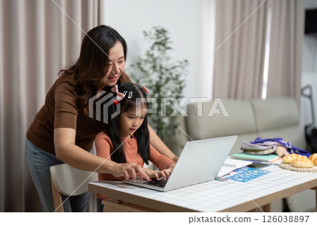 Back to School and Learning Together. A mother helps her daughter with online studies at home. 126038897