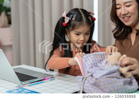 Back to School and Preparing for Learning. A child organizes school supplies with parental guidance. 126038898
