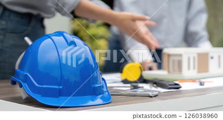 Sustainability and Construction Planning. A blue hard hat on a table during a sustainable building project discussion. 126038960