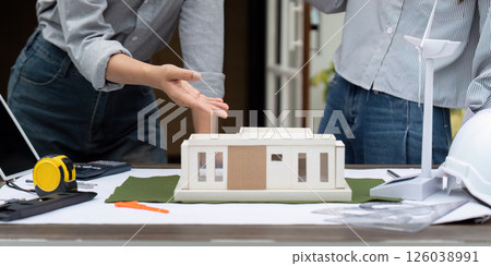 Eco-Friendly Building Models and Collaboration. Two architects discussing sustainable architecture with a focus on renewable energy. 126038991