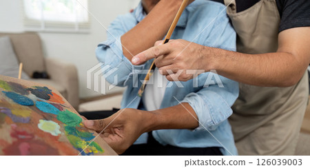 Gay couple enjoying painting activity together at home 126039003