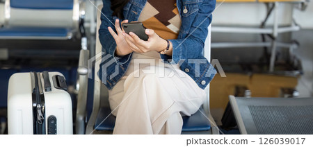 Travel journey: young woman checking smartphone at airport lounge Travel journey: young woman checking smartphone at airport lounge 126039017