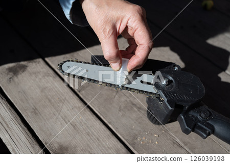 A man repairs an electric saw. Lubrication of the chain. A man repairs an electric saw. Lubrication of the chain. 126039198