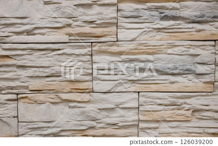 Textured stone wall featuring a natural, rustic design with warm tones and intricate patterns in a contemporary setting 126039200