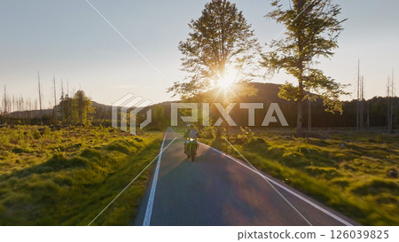 Motorcycle Rider in a Beautiful Sunset Rural Landscape. Action Sports Shot of Touring Motorbike. Motorcycle Rider in a Beautiful Sunset Rural Landscape. Action Sports Shot of Touring Motorbike. 126039825