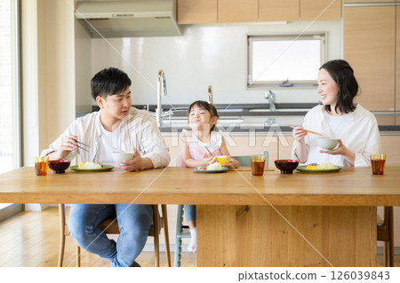 一家三口在漂亮的木屋吃飯，在餐桌上微笑 126039843