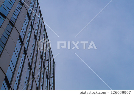 Exterior of modern multi-storey skyscraper building in central business district of city against background of blue haze sky. Office space for rent, doing business in premises with good natural light Exterior of modern multi-storey skyscraper building in central business district of city against background of blue haze sky. Office space for rent, doing business in premises with good natural light 126039907