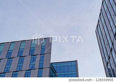 Buildings exteriors made in modern minimalist design with use of energy-saving glass, aluminum profiles, ceramic structural elements with thermal insulation of facade. Blue sky background, copy space Buildings exteriors made in modern minimalist design with use of energy-saving glass, aluminum profiles, ceramic structural elements with thermal insulation of facade. Blue sky background, copy space 126039908